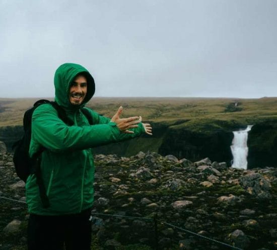 viager amb motxilla ensenyant una cascada al bell mitg d'islàndia