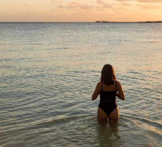 detall d'una noia al mar mirant el capvespre