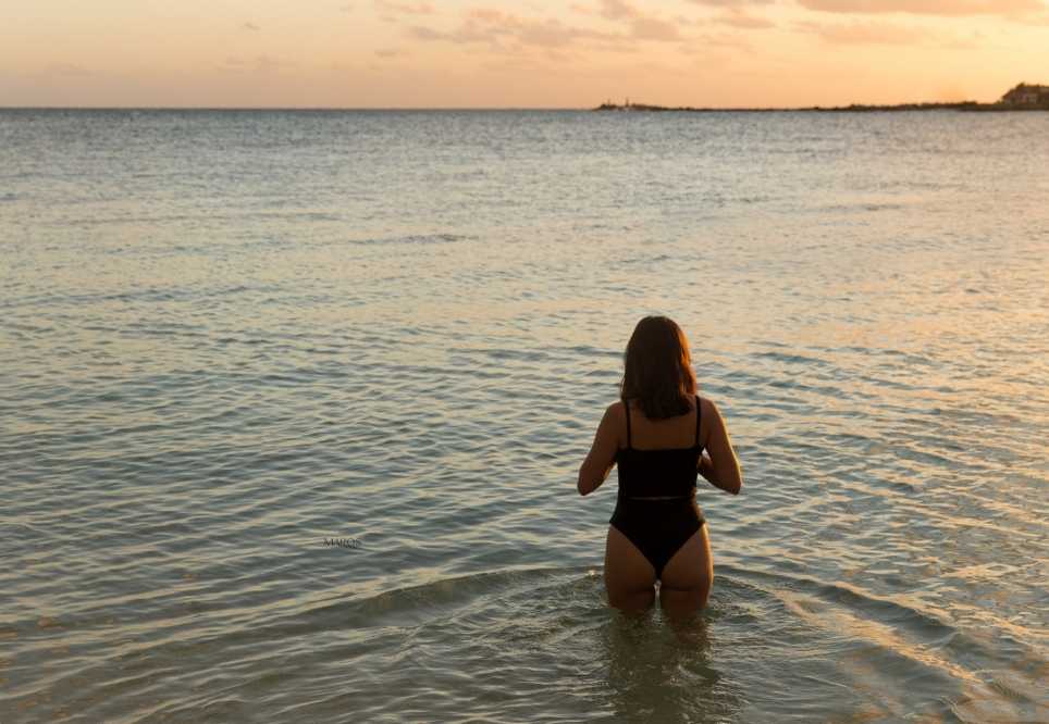 detall d'una noia al mar mirant el capvespre